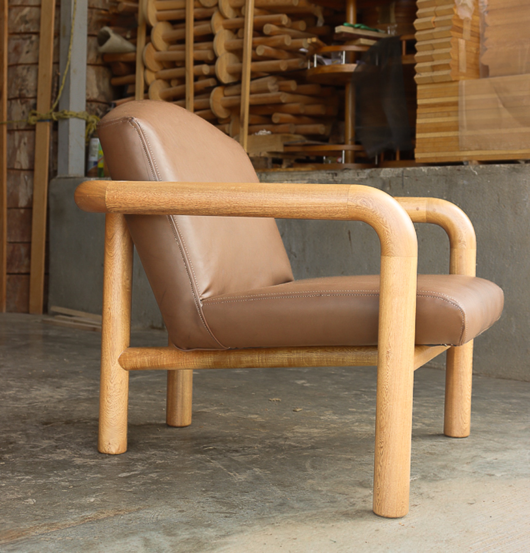 Sillón tubular de madera con asiento y respaldo tapizados en piel